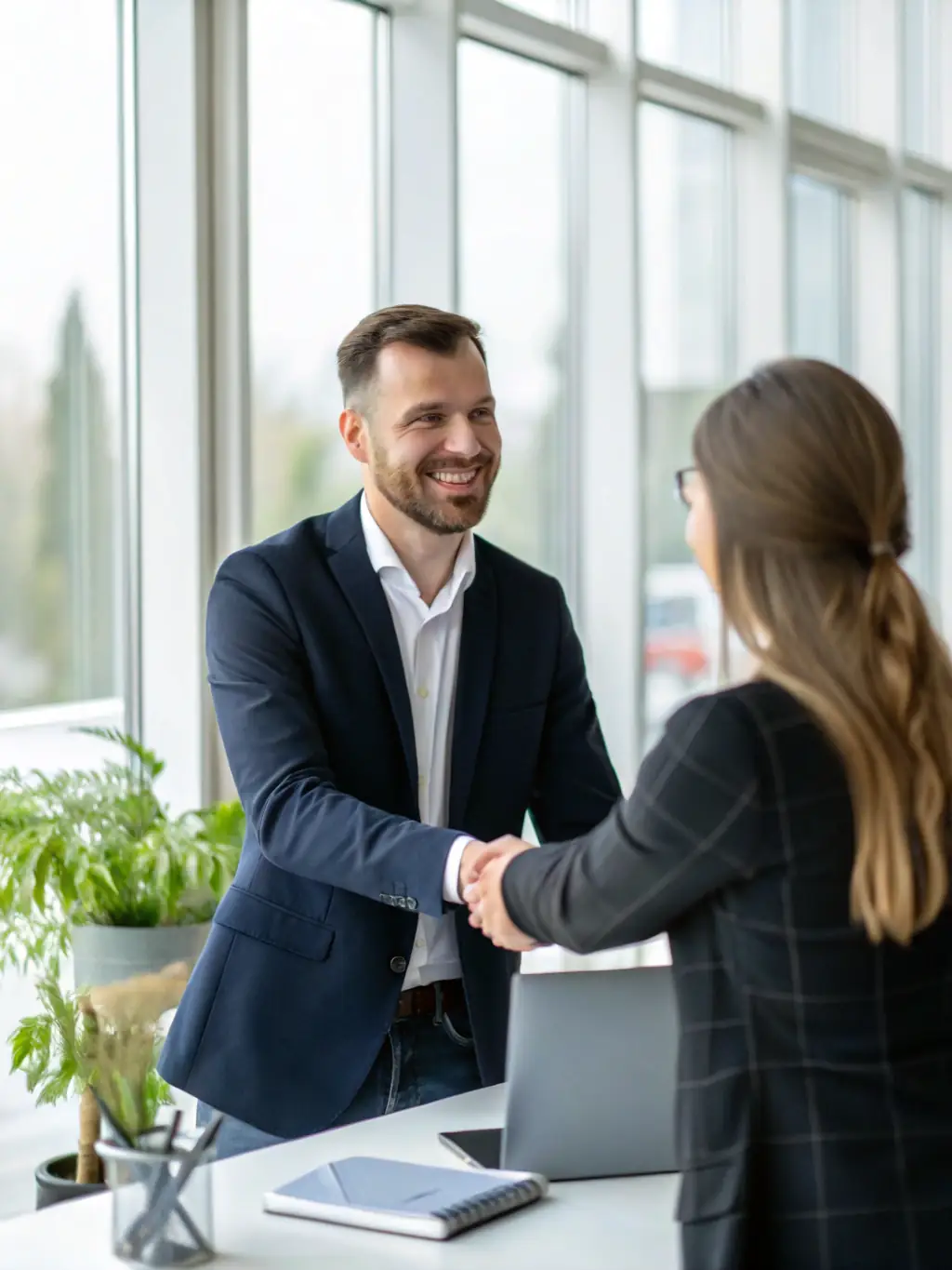 A professional businessman in a suit shaking hands with a client over a desk, symbolizing trust and agreement in life insurance, with a focus on financial security for families.